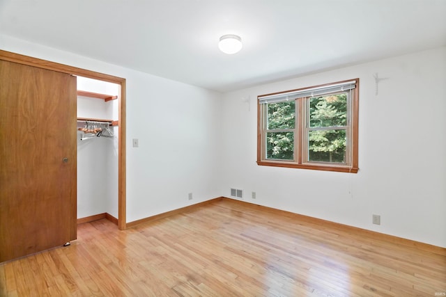 unfurnished bedroom with light hardwood / wood-style flooring, a walk in closet, and a closet