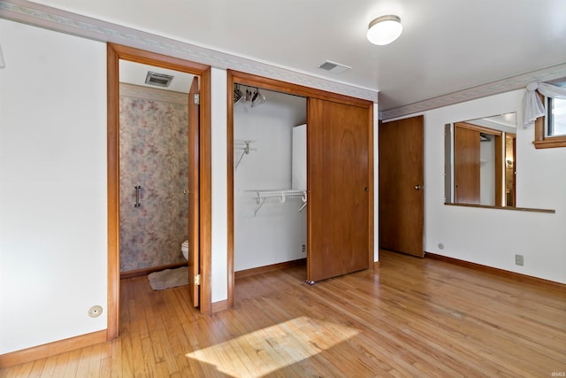 unfurnished bedroom featuring light wood-type flooring and ensuite bath