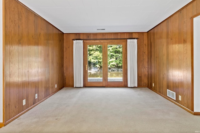 spare room with wood walls and light colored carpet