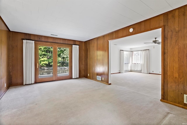 spare room with wood walls, light colored carpet, and ceiling fan