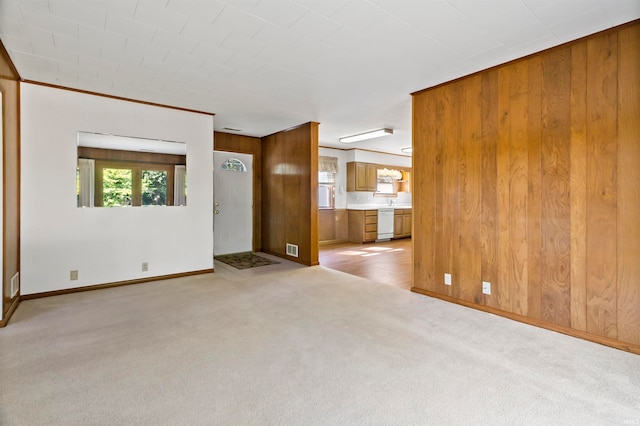 unfurnished living room with wood walls and light carpet