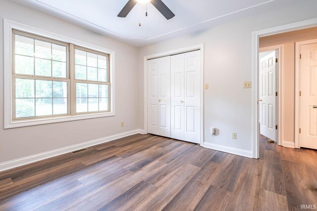 unfurnished bedroom featuring dark wood-type flooring, ceiling fan, and a closet