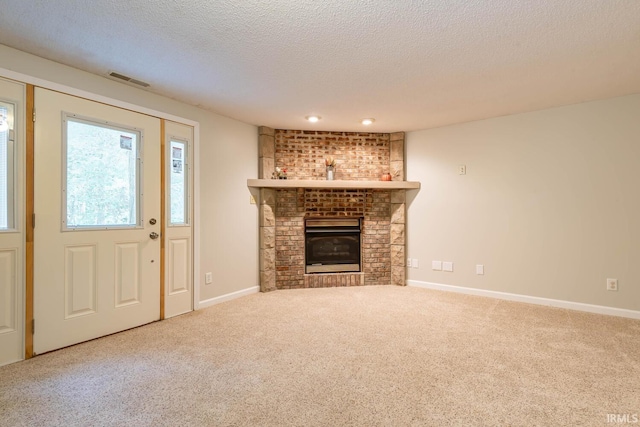 unfurnished living room with carpet floors, a fireplace, and a textured ceiling