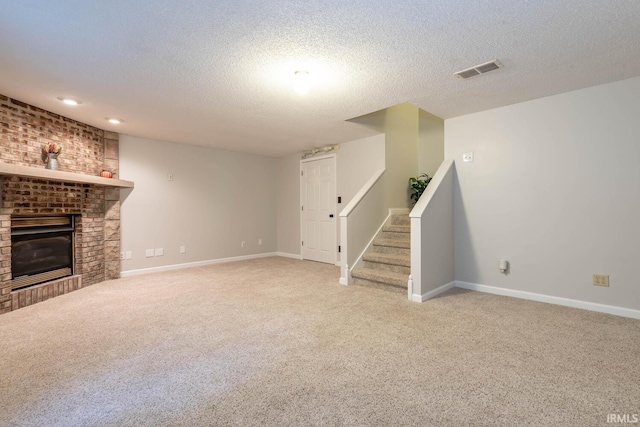 basement featuring a textured ceiling, light colored carpet, and a brick fireplace