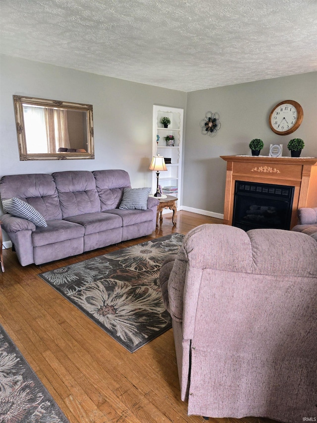 living room featuring a textured ceiling, built in features, and hardwood / wood-style floors