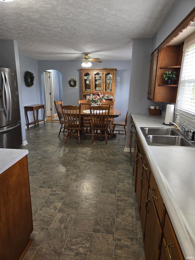 dining space featuring a textured ceiling, sink, and ceiling fan