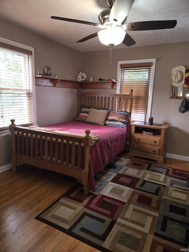 bedroom with a textured ceiling, ceiling fan, and hardwood / wood-style floors