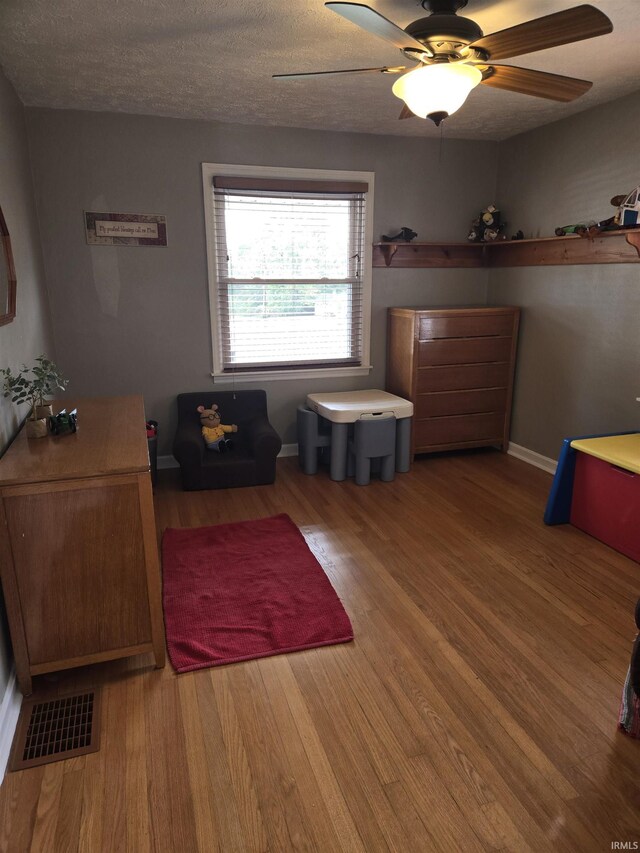 interior space featuring ceiling fan, wood-type flooring, and a textured ceiling