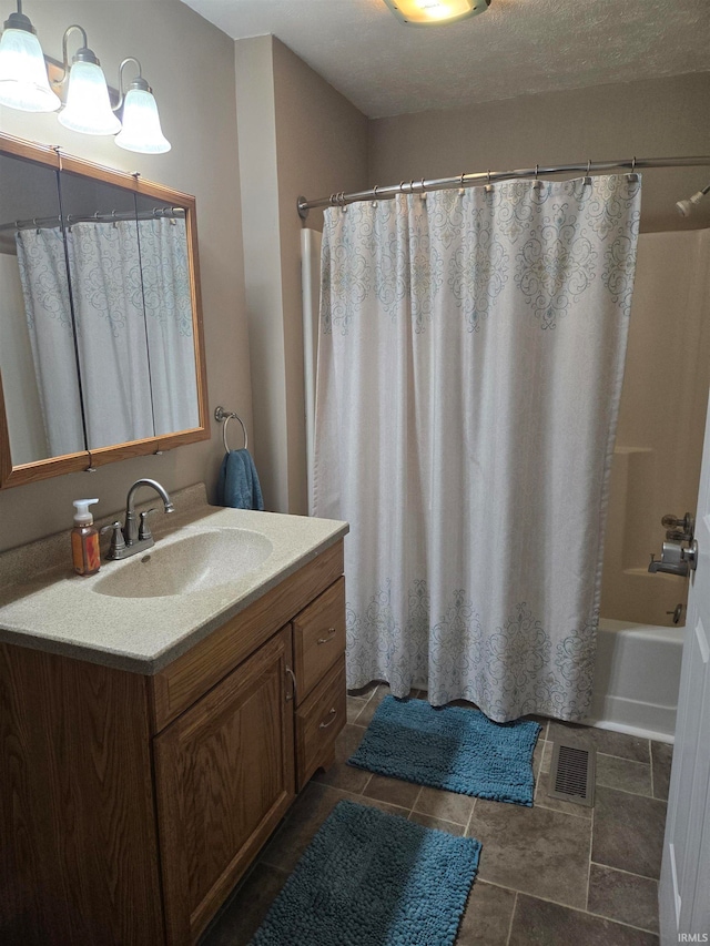 bathroom featuring a textured ceiling, vanity, and shower / bath combo