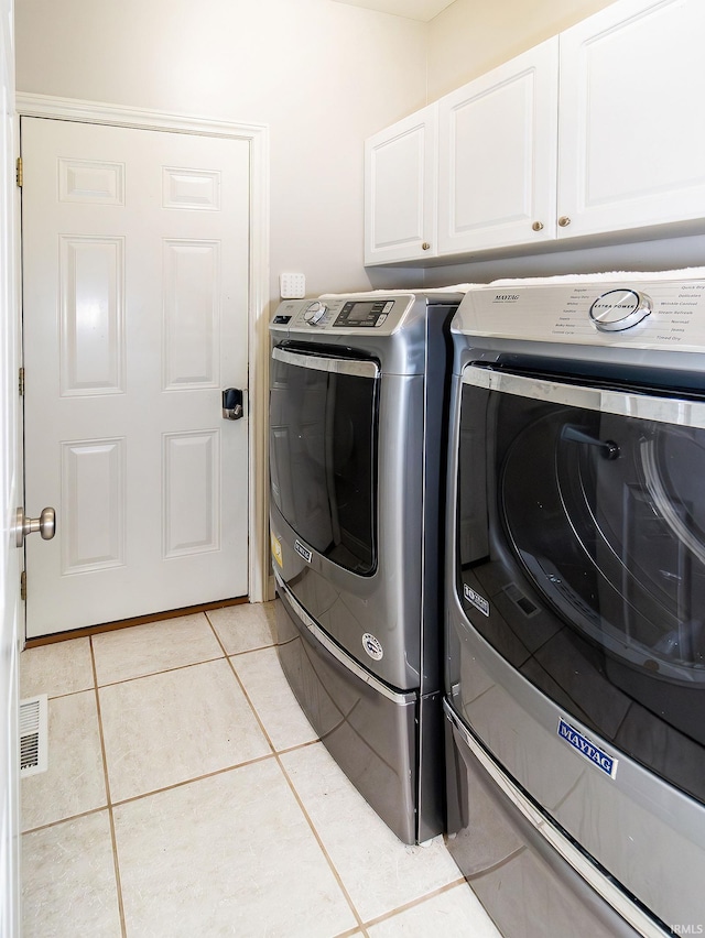 laundry room with cabinets, separate washer and dryer, and light tile patterned floors