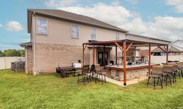 rear view of house featuring fence, outdoor dry bar, a lawn, and brick siding