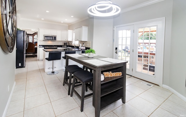 tiled dining room featuring ornamental molding and sink