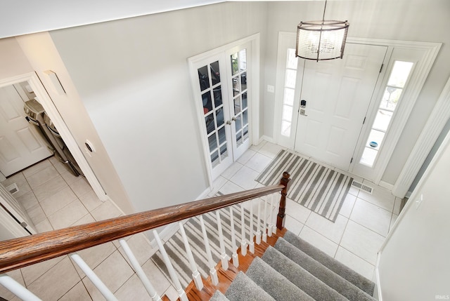 tiled entrance foyer featuring a notable chandelier and french doors