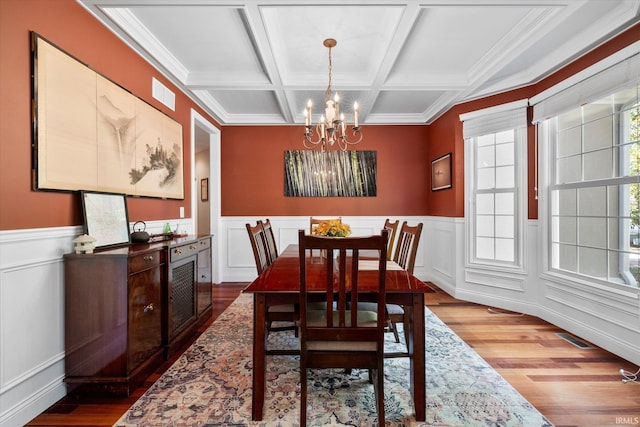 dining room featuring coffered ceiling, an inviting chandelier, beamed ceiling, and wood-type flooring