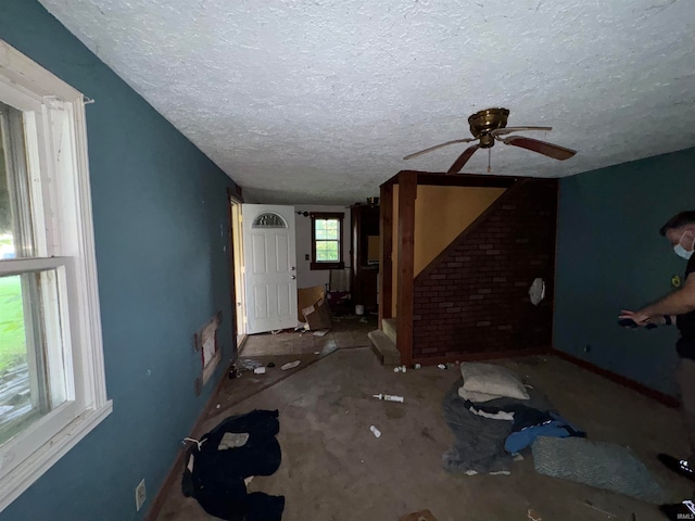 unfurnished living room with a textured ceiling and ceiling fan