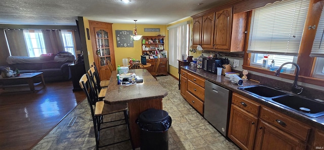 kitchen with plenty of natural light, dishwasher, sink, and a kitchen island