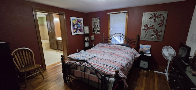 bedroom with baseboards, wood finished floors, and connected bathroom