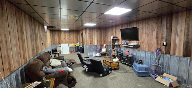 interior space with a paneled ceiling, wooden walls, and carpet flooring