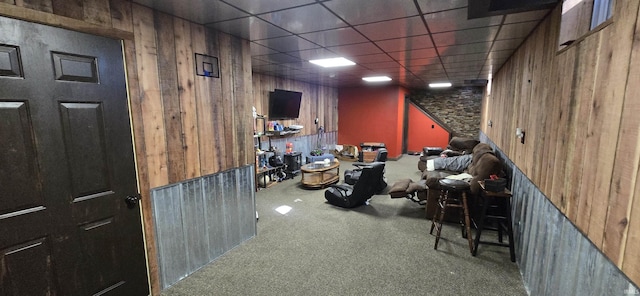 interior space featuring wood walls, a drop ceiling, and carpet flooring