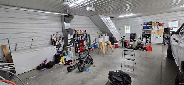 garage with a garage door opener, white refrigerator with ice dispenser, and metal wall