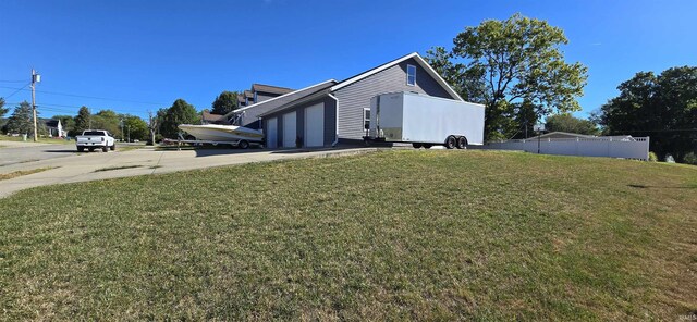 view of home's exterior with an attached garage, fence, concrete driveway, and a yard