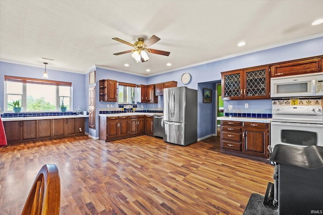 kitchen featuring backsplash, hardwood / wood-style flooring, crown molding, appliances with stainless steel finishes, and ceiling fan