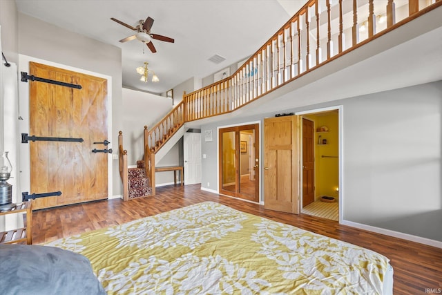 bedroom featuring dark hardwood / wood-style flooring, ensuite bathroom, a barn door, ceiling fan, and a towering ceiling