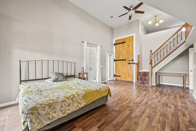 bedroom featuring high vaulted ceiling, hardwood / wood-style flooring, ceiling fan, and a barn door