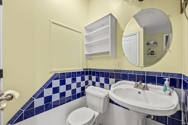 bathroom with tile walls, toilet, and sink