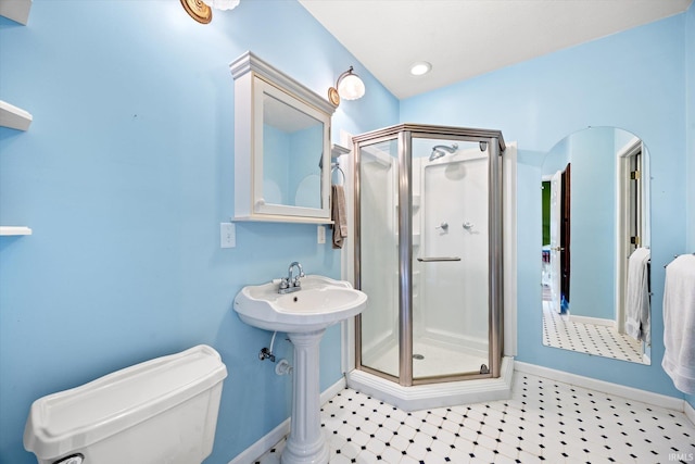 bathroom featuring a shower with door and toilet