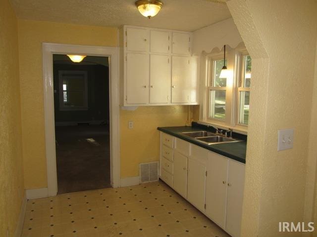 kitchen with white cabinetry, decorative light fixtures, and sink