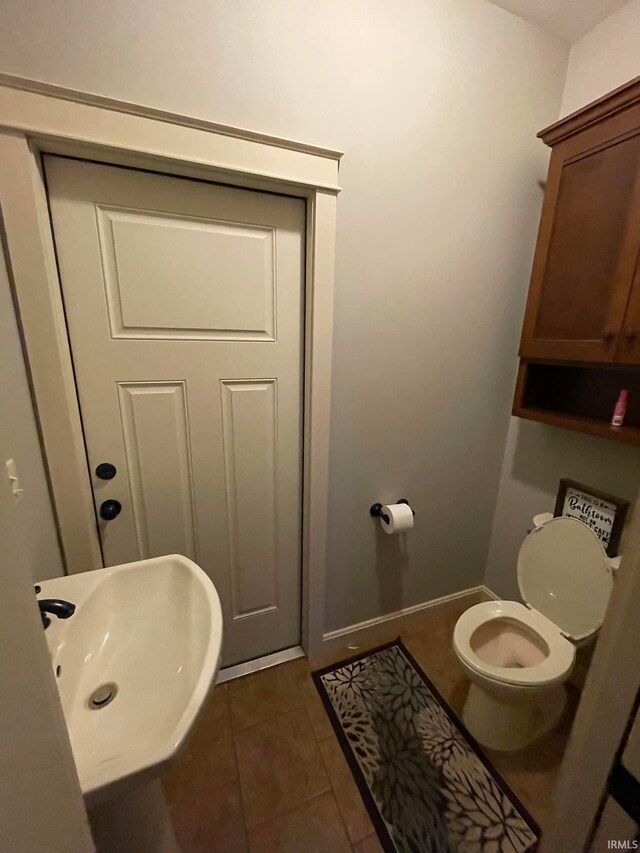 bathroom with toilet, sink, and tile patterned floors