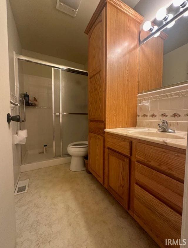 bathroom featuring a shower with door, vanity, toilet, and tasteful backsplash