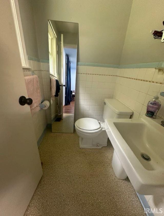 bathroom featuring tile walls and toilet