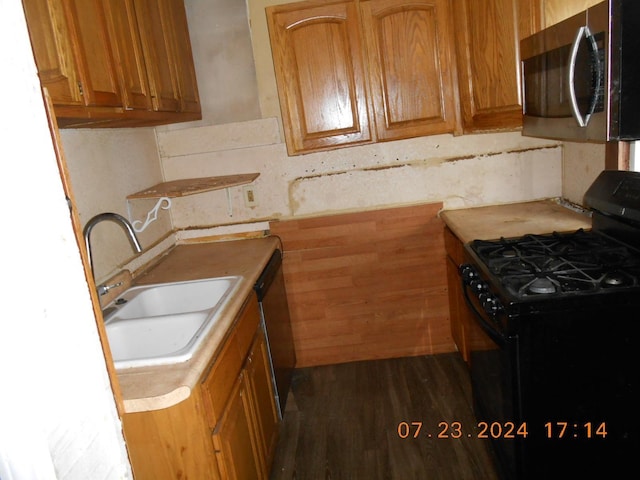 kitchen featuring a sink, stainless steel appliances, dark wood-style flooring, and light countertops