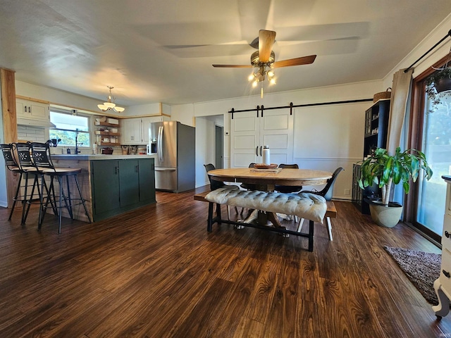 dining area with ceiling fan, a barn door, and dark hardwood / wood-style floors