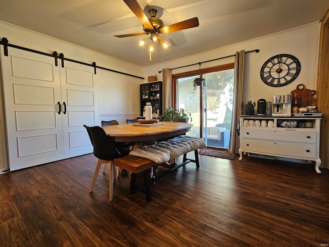 dining room featuring a barn door, ceiling fan, and dark wood-type flooring