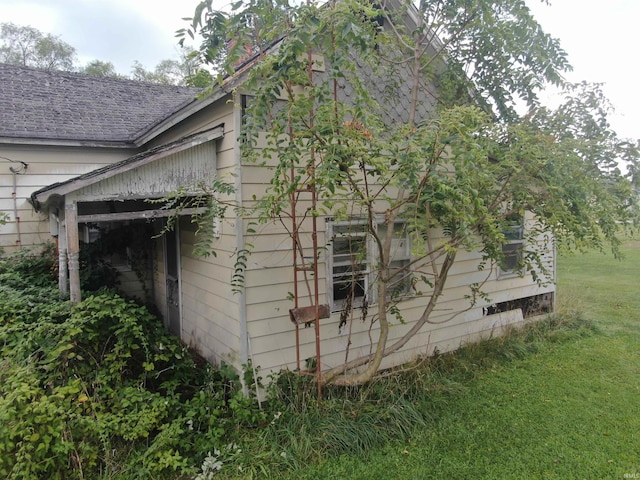 view of property exterior with a lawn and roof with shingles