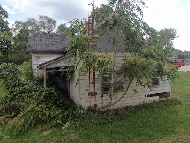 view of side of property with a yard and roof with shingles