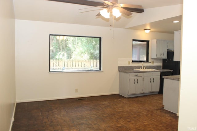 kitchen featuring ceiling fan, sink, white cabinetry, and vaulted ceiling