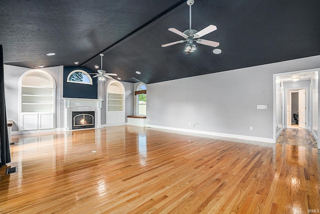 unfurnished living room with light hardwood / wood-style flooring, ceiling fan, high vaulted ceiling, and a textured ceiling