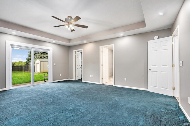 unfurnished bedroom featuring access to outside, carpet flooring, a tray ceiling, and ceiling fan