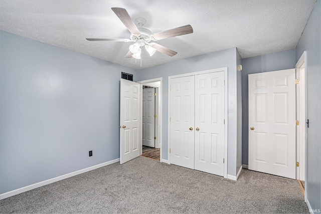 unfurnished bedroom with ceiling fan, a textured ceiling, a closet, and carpet