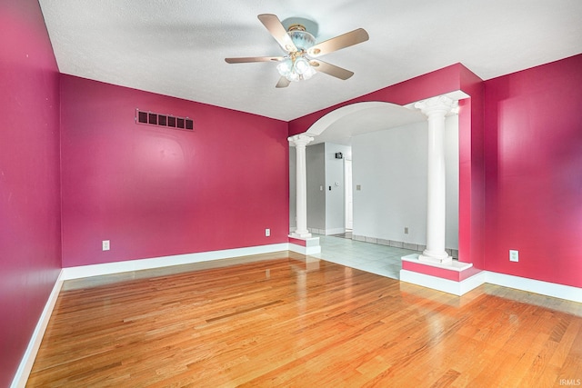 unfurnished room featuring a textured ceiling, ceiling fan, hardwood / wood-style flooring, and ornate columns