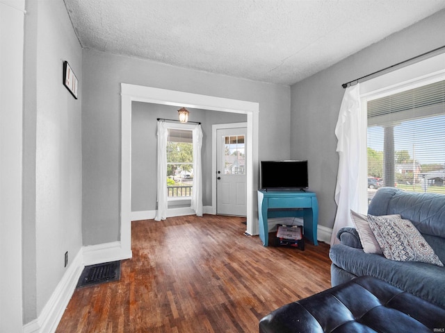 living room featuring a textured ceiling and dark hardwood / wood-style floors