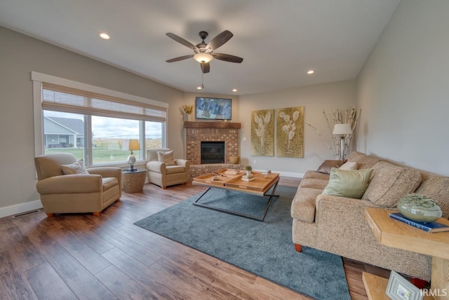 living room featuring a fireplace, hardwood / wood-style flooring, and ceiling fan