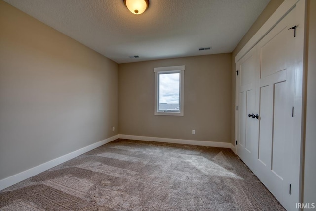 unfurnished bedroom with a textured ceiling and carpet floors