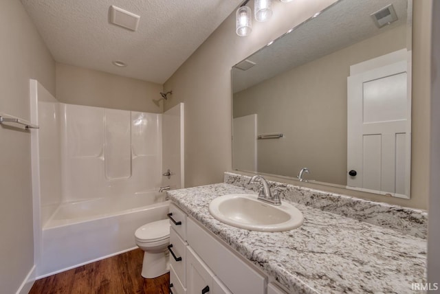 full bathroom with hardwood / wood-style floors, toilet,  shower combination, vanity, and a textured ceiling