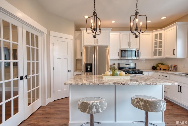 kitchen with white cabinetry, stainless steel appliances, decorative light fixtures, and a chandelier