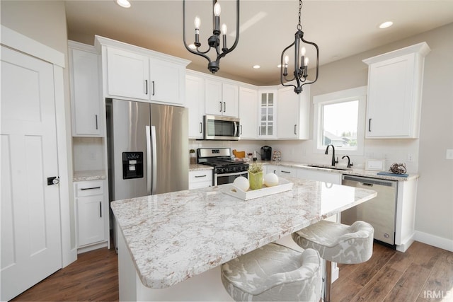 kitchen featuring appliances with stainless steel finishes, white cabinetry, a kitchen island, and an inviting chandelier